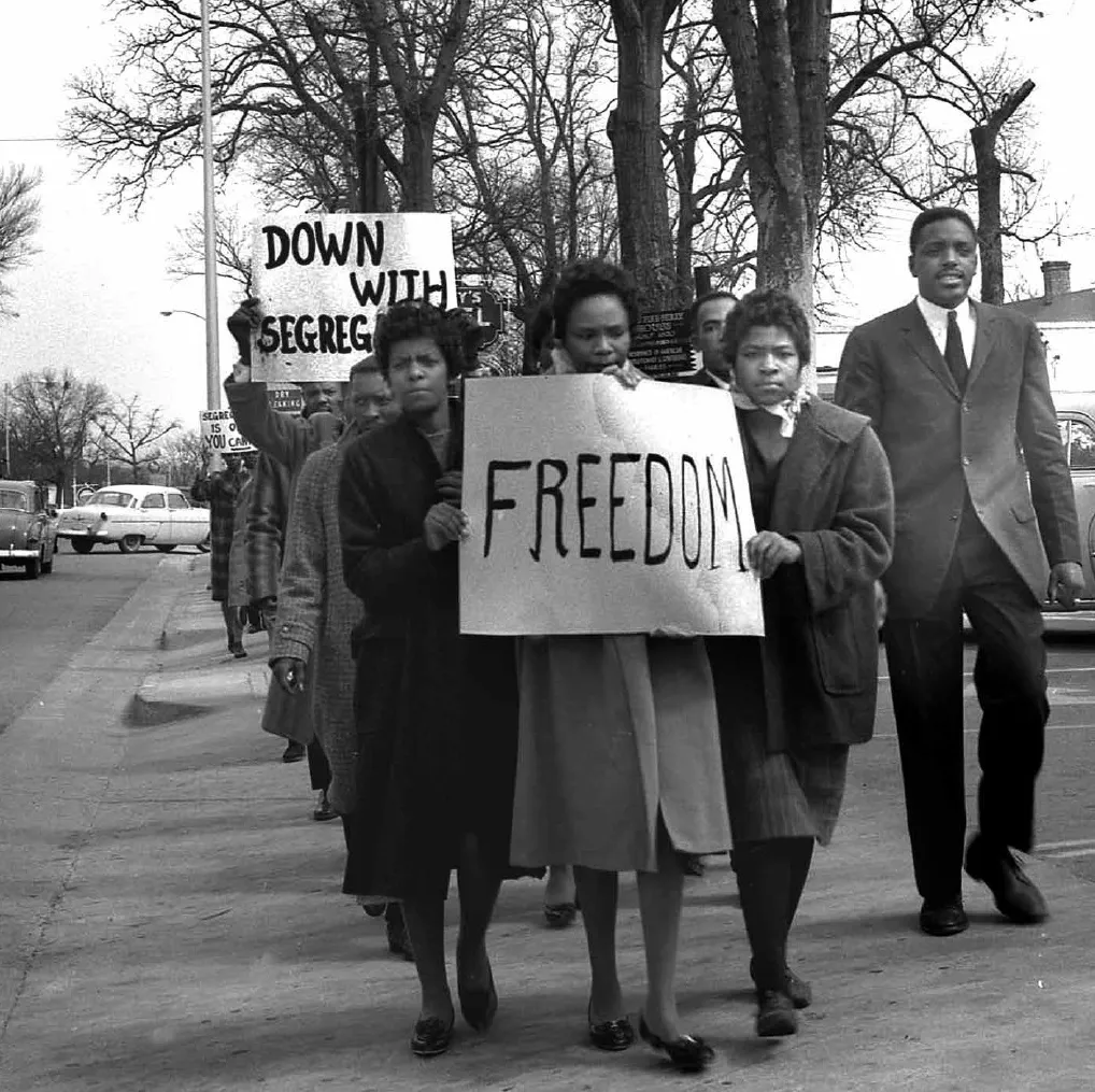 Protesters march with signs saying