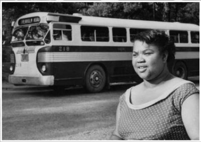 A woman speaking in front of a bus.