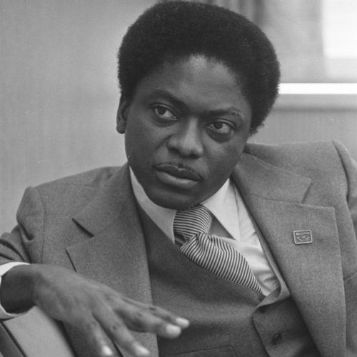 A young James E. Clyburn in a suit sits on a sofa.
